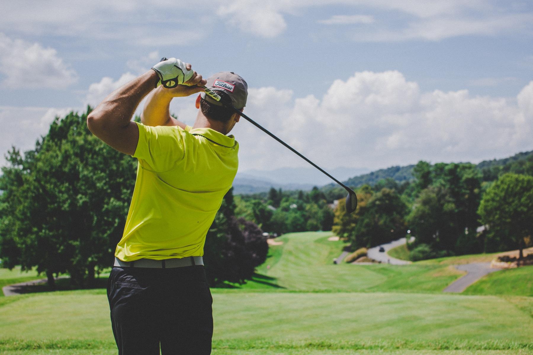 A picture of a person golfing wearing a green shirt.