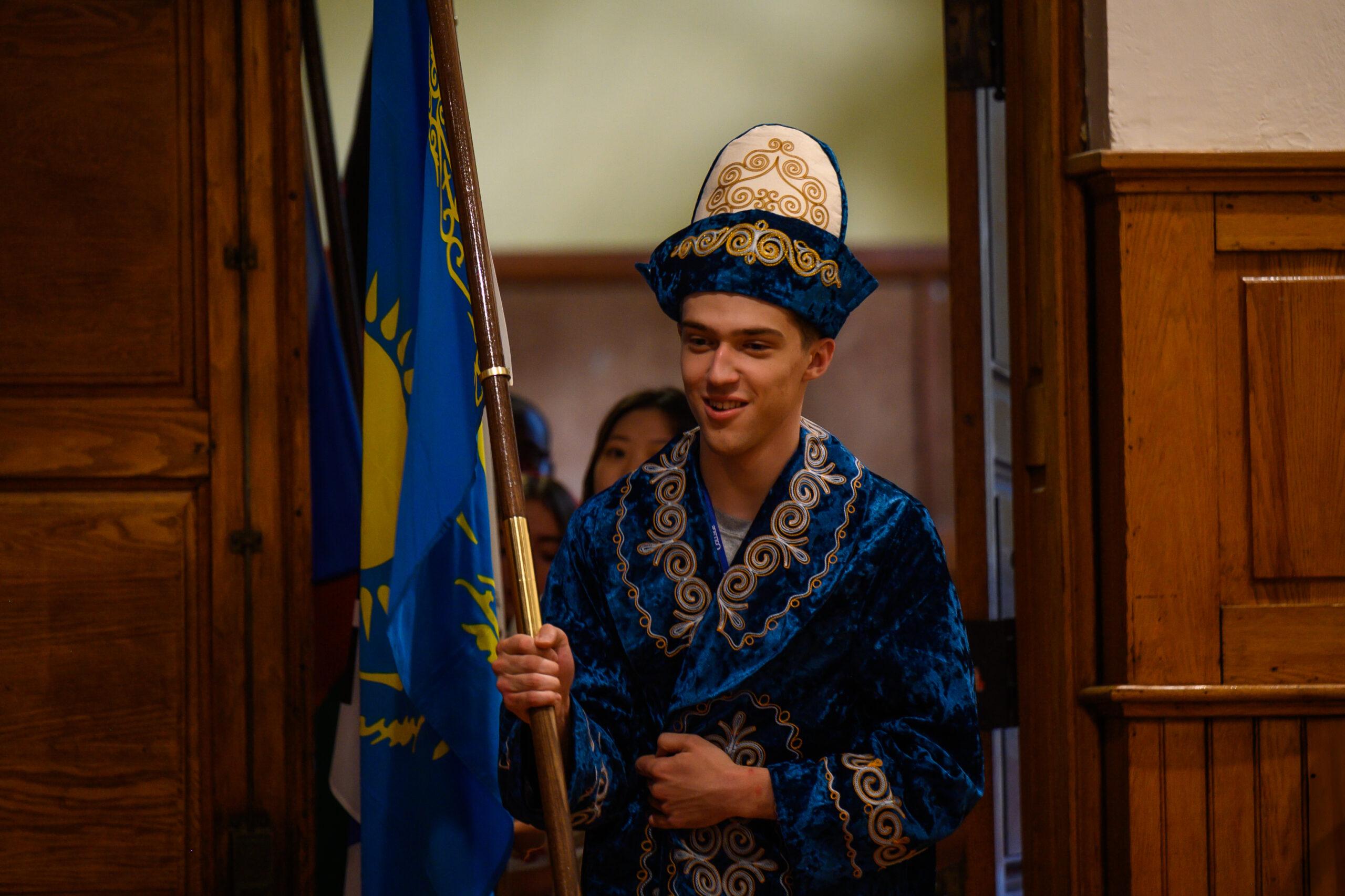 An international student makes his way into Phelps Stokes, carrying his country's flag while wearing traditional attire from his home country.